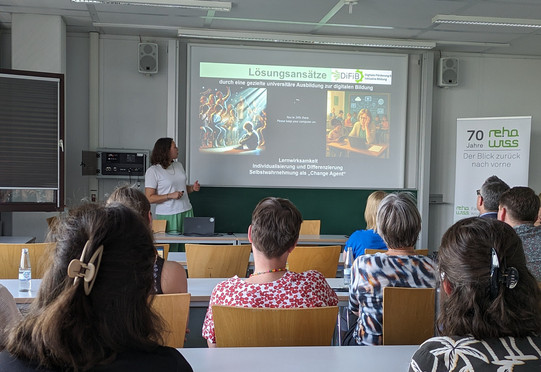 Foto von Jun.-Prof. Dr. Jana Jungjohann während des Vortrags. Auf der Folie sind die beiden Perspektiven zu den Lösungsansätze zur Verringerung des disability digital divides des Fachgebiets durch ein Bild einer verzweifelten Lehrkraft und eines sozial ausgeschlossenen Jungen visualisiert. 