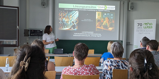 Foto von Jun.-Prof. Dr. Jana Jungjohann während des Vortrags. Auf der Folie sind die beiden Perspektiven zu den Lösungsansätze zur Verringerung des disability digital divides des Fachgebiets durch ein Bild einer verzweifelten Lehrkraft und eines sozial ausgeschlossenen Jungen visualisiert.