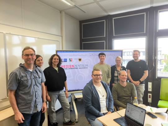 Gruppenfoto der Teilnehmenden des Austauschs: Claudia Wierz (Leitung des Medienzentrums), Burkhard Pesch (Medienberater der Zentren für schulpraktische Lehrerausbildung), Daniel Baldauf (Medienberater der Bezirksregierung Arnsberg mit dem Schwerpunkt Grundschule), Anna-Louisa Jesudason (Medienberaterin der Bezirksregierung Arnsberg mit Förderschulexpertise), Marc Litzmanski (Medienberater der Bezirksregierung Arnsberg für Gesamtschulen und Grundschulen), Mirco Urbaniak (Medienberater der Bezirksregierung Arnsberg für Gymnasien) und Sven Stumpe (Medienberater der Bezirksregierung Arnsberg für Grundschulen mit dem Schwerpunkt Programmieren) sowie Gastgeberin Jun.-Prof. Dr. Jana Jungjohann.