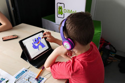 Junge im roten Tshirt bedient ein Tablet und trägt Kopfhörer
