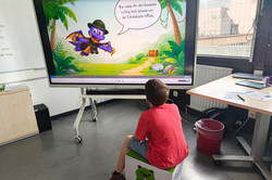 Junge sitzt vor dem Smartboard und liest eine Aufgabenstellung