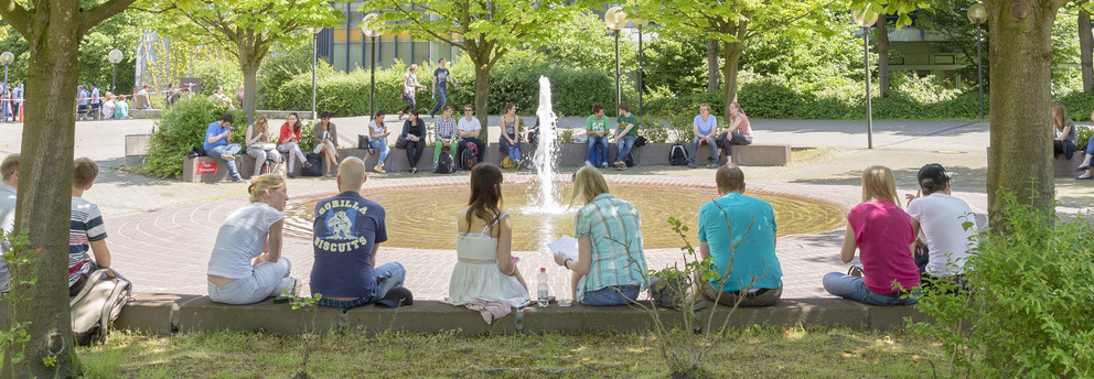 Studenten sitzen im Sommer am Brunnen des Martin-Schmeißer-Platzes